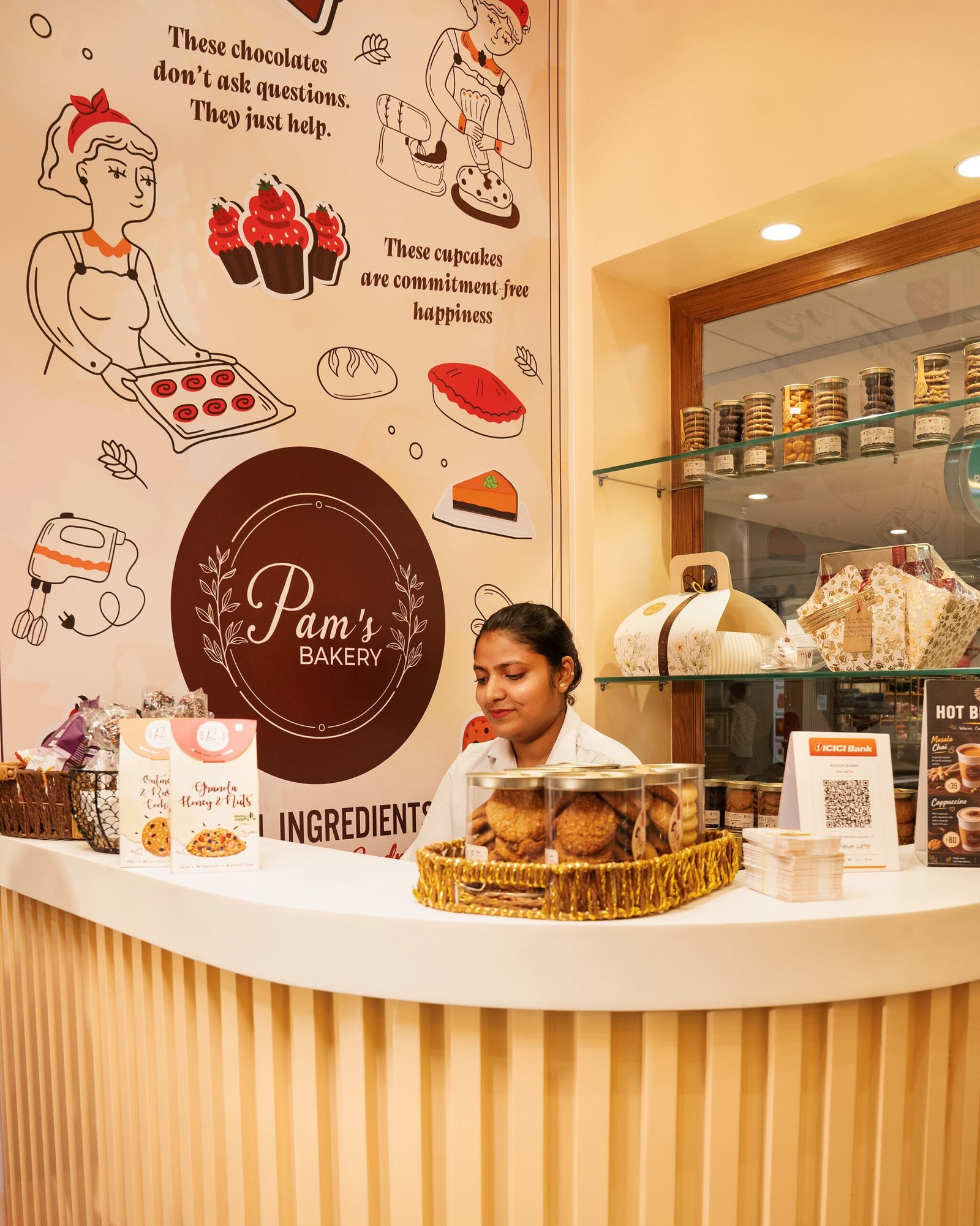 Pam’s Bakery counter with a staff member, bakery products, and branded wall artwork