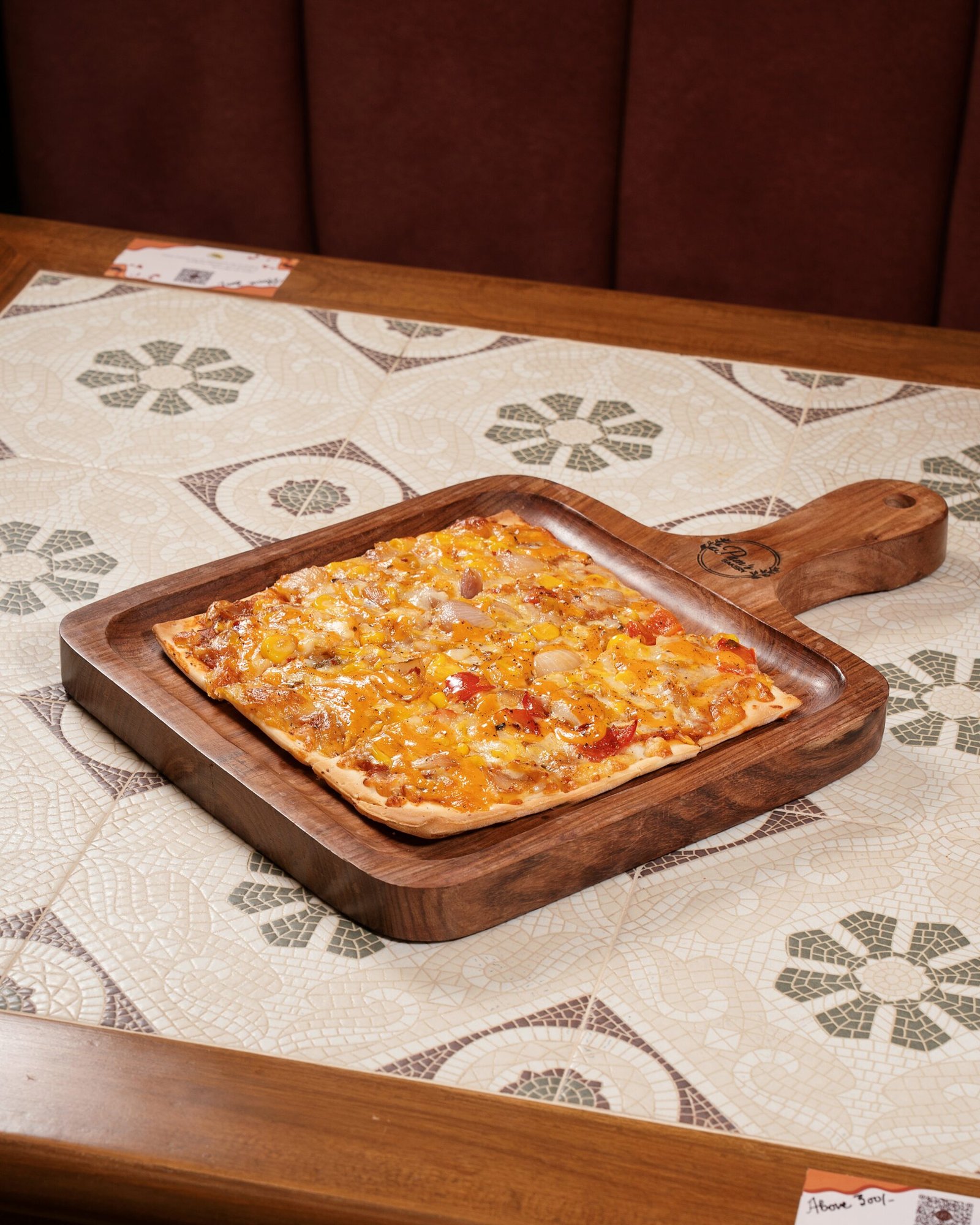 Freshly baked vegetable pizza with melted cheese served on a wooden board at Pam's Bakery