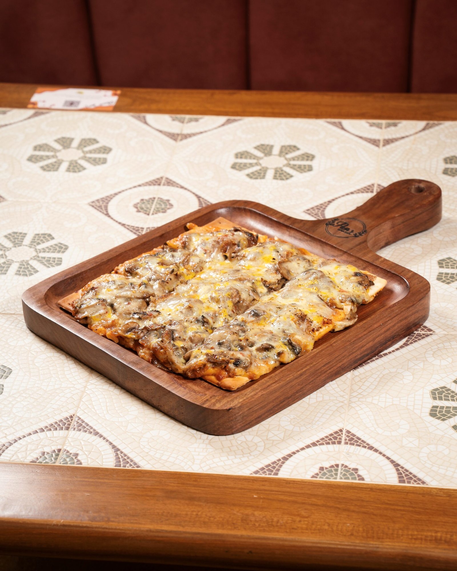Freshly baked cheesy pizza served on a wooden board at Pam's Bakery