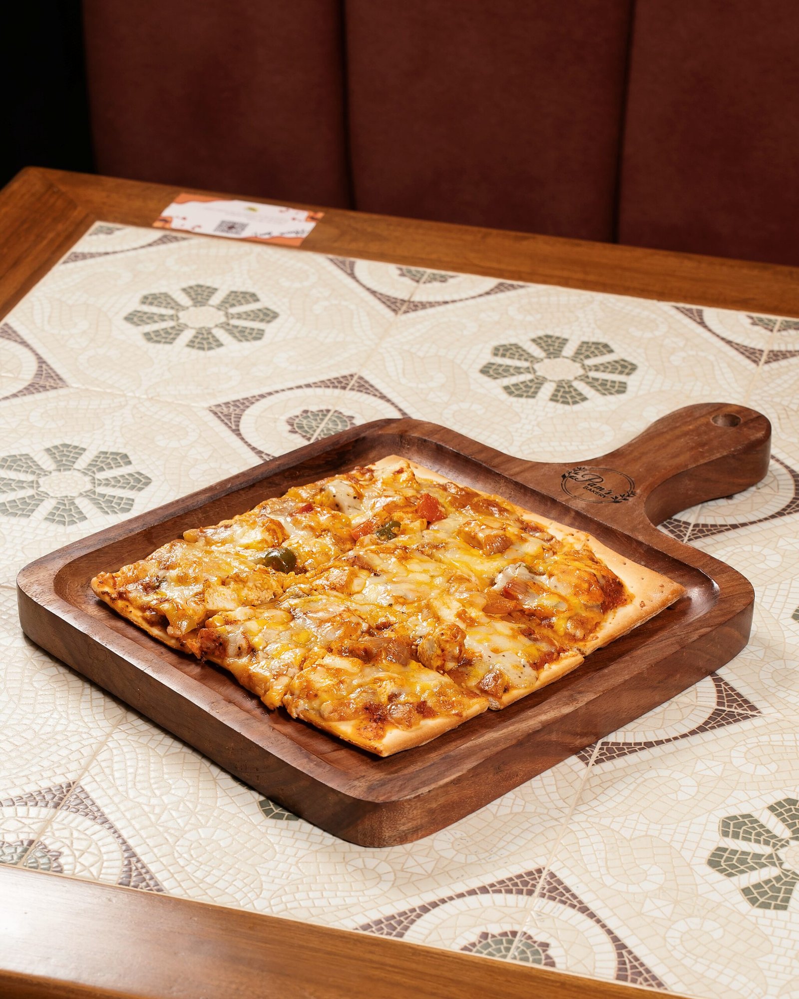 Freshly baked cheesy vegetable pizza served on a wooden board at Pam's Bakery