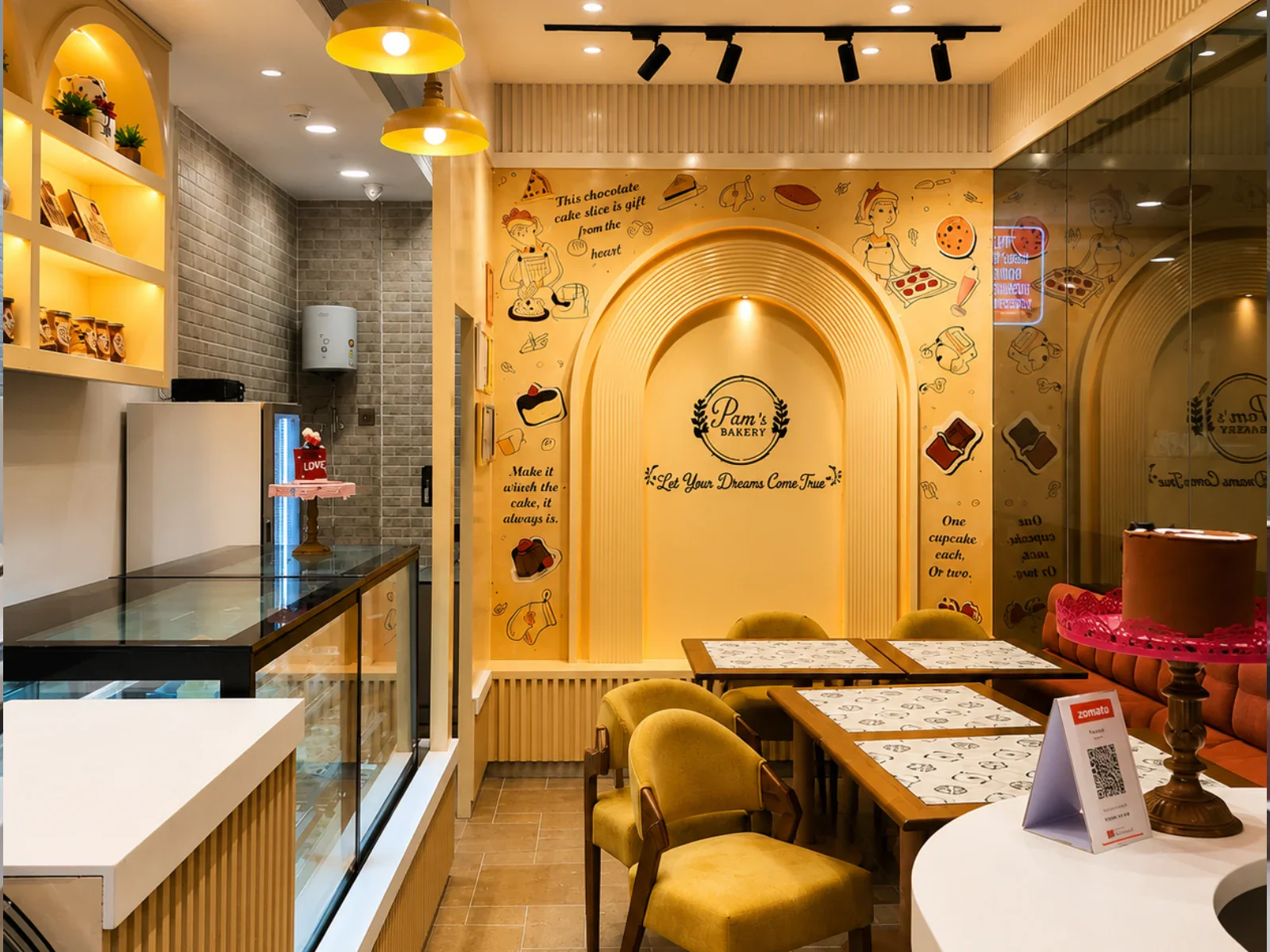 Pams Bakery Cafe seating area with branded wall decor, tables, and dessert display